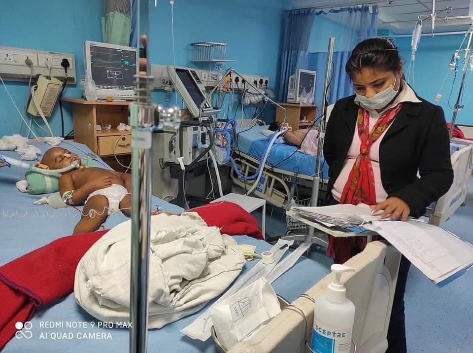 A child receiving critical care in a hospital while a Karm National volunteer reviews medical documents